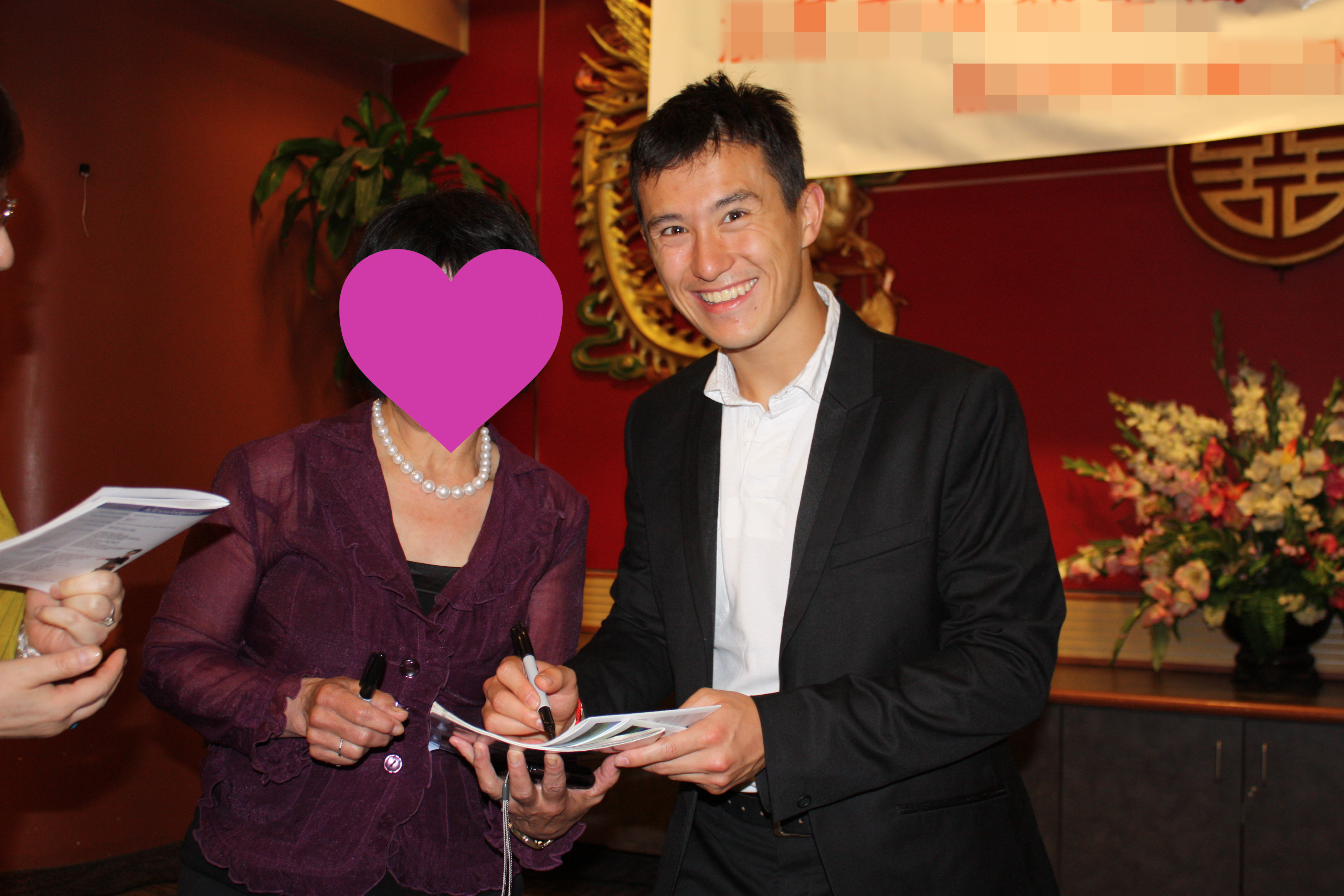 Patrick Chan fan Happylife getting his autograph at a fundraising dinner, May 2012. He is smiling in the photo.